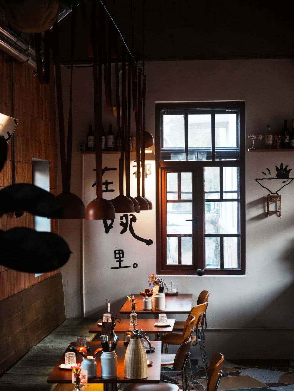 Toplo osvijetljen prostor restorana s drvenim stolovima.